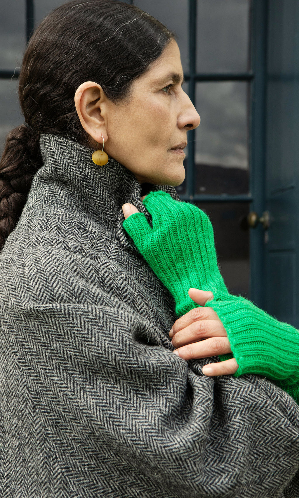 Plümo  A person in a herringbone coat stands as another hand in Green Wristwarmers holds their collar.