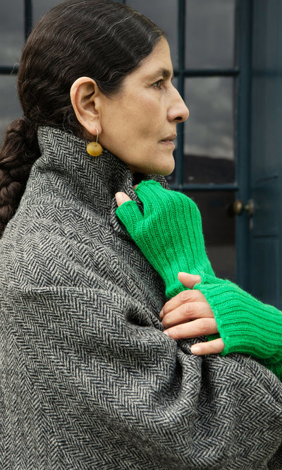 Plümo  A person in a herringbone coat stands as another hand in Green Wristwarmers holds their collar.