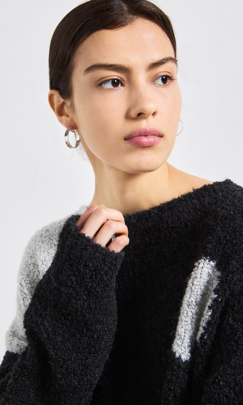 Plümo- Woman with dark hair in Silver Pebble Hoops and a black-and-white fuzzy sweater, looking off to the side.