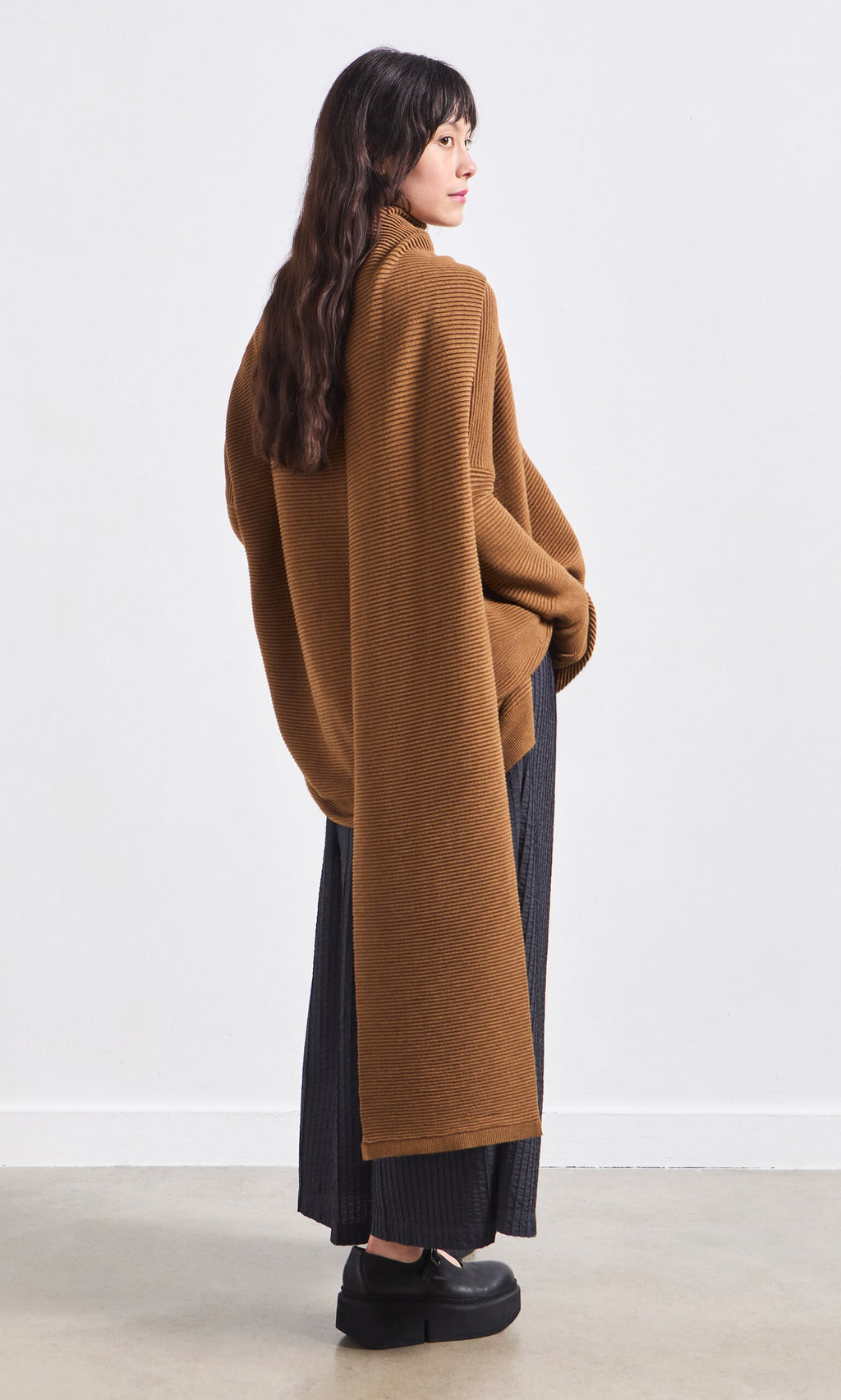Plümo- Woman wearing the Janie Scarf in Chestnut, long skirt, and black shoes against a plain white background.