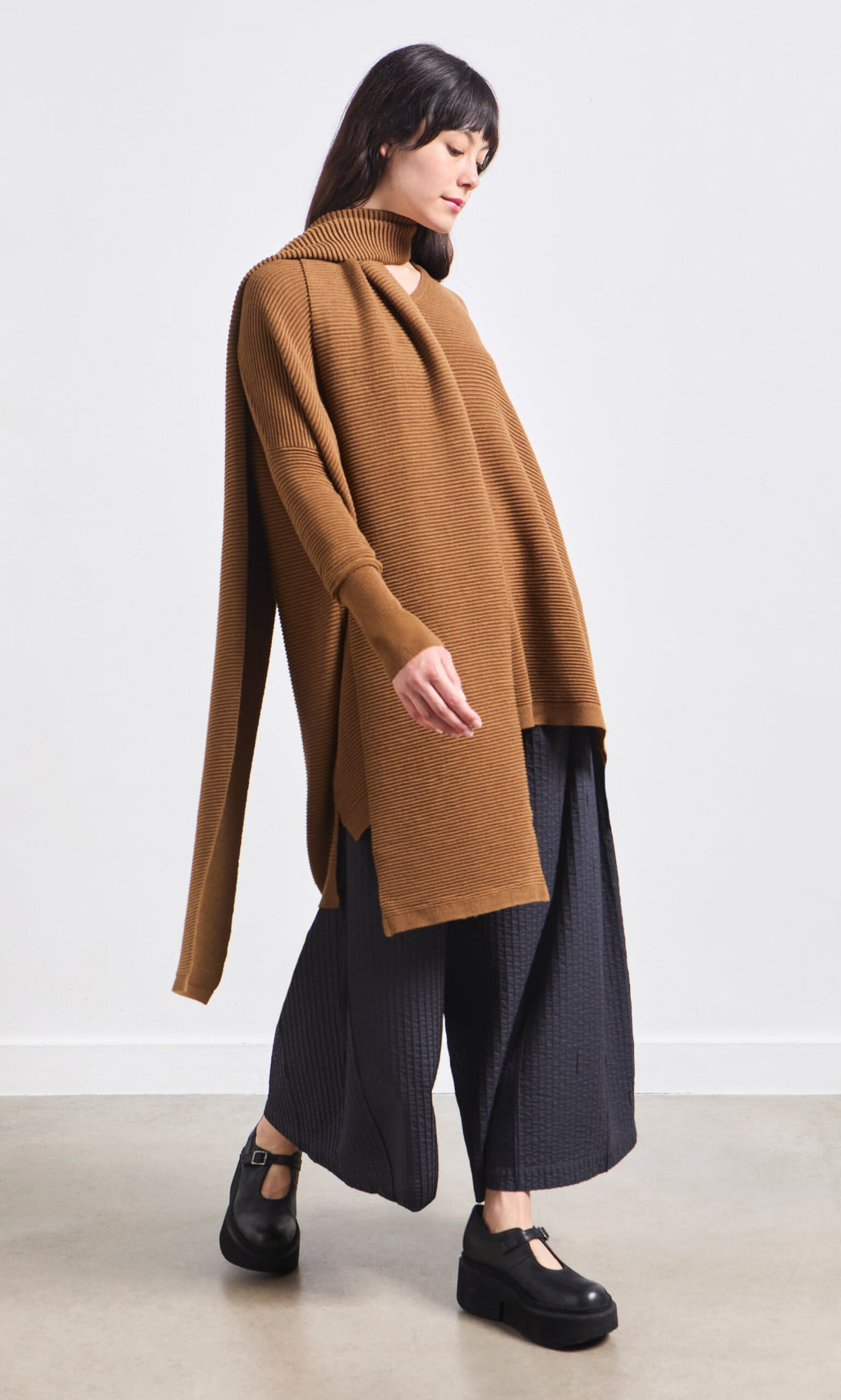 Plümo- Woman in a loose brown top, black wide-leg pants, and the Janie Scarf - Chestnut against a plain background.