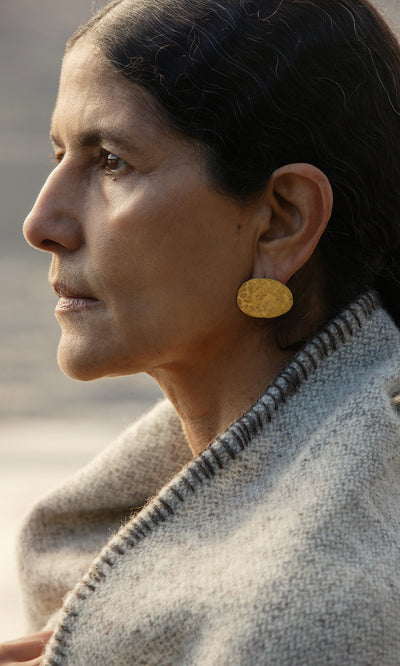 Plümo  A woman in profile wears the Cohen Earrings and a gray wool shawl, gazing thoughtfully into the distance.