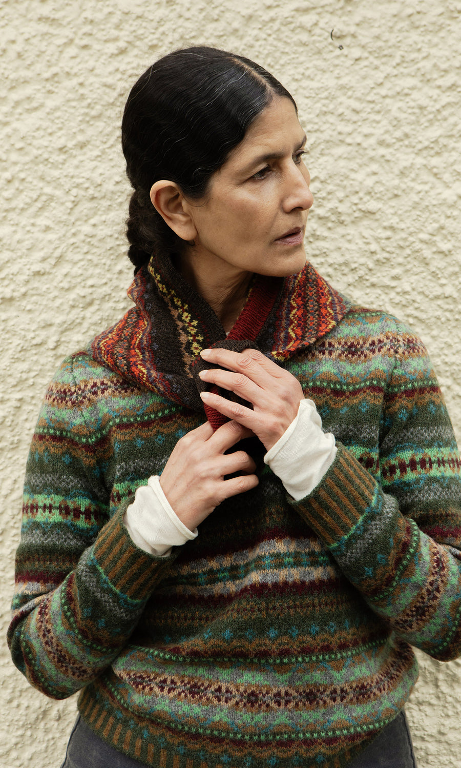 Plümo  A woman in a Lenie Necktie and scarf stands by a textured wall, gazing to her right.