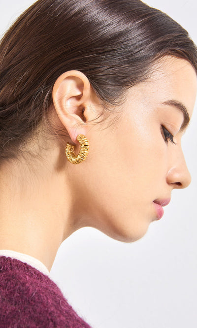 Plümo- Woman with dark hair in profile wears Lili Hoops and a burgundy top against a plain background.