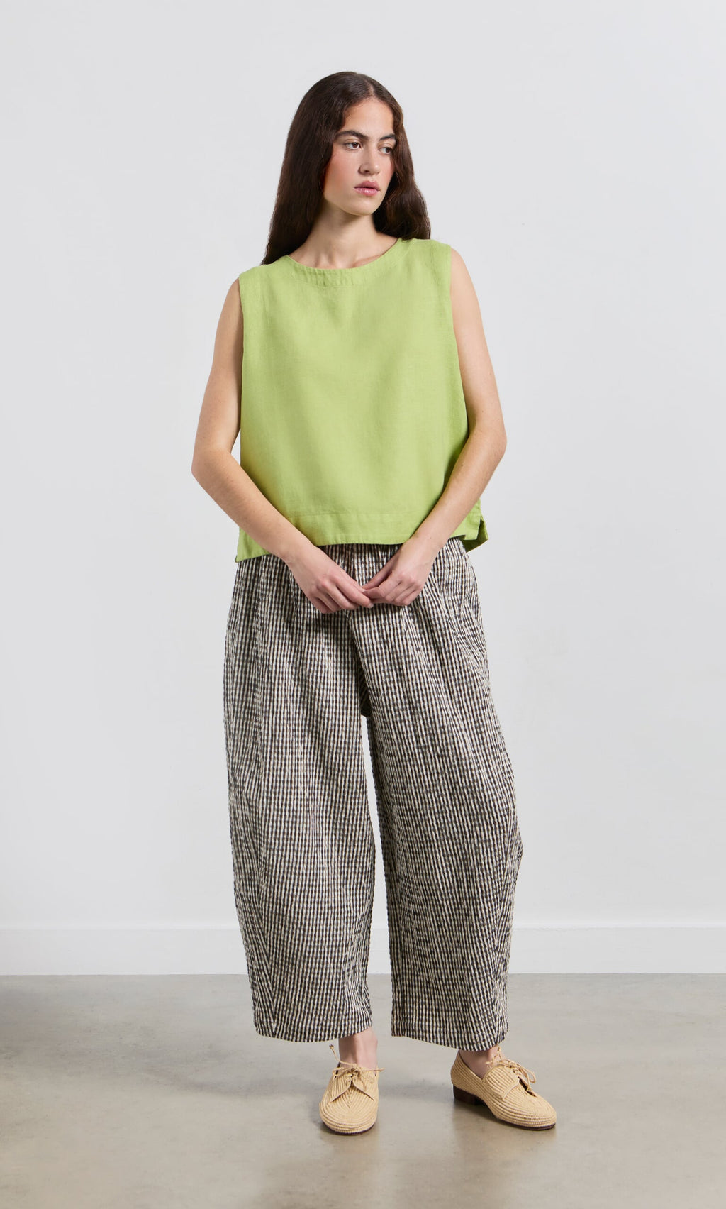 Plümo- Woman wears the Linda Top - Sorrel with loose checkered pants, standing against a plain white background.