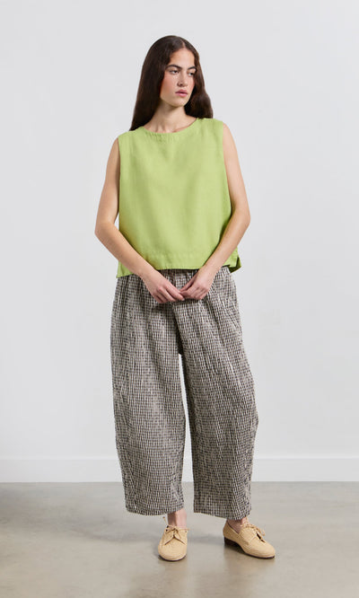 Plümo- Woman wears the Linda Top - Sorrel with loose checkered pants, standing against a plain white background.