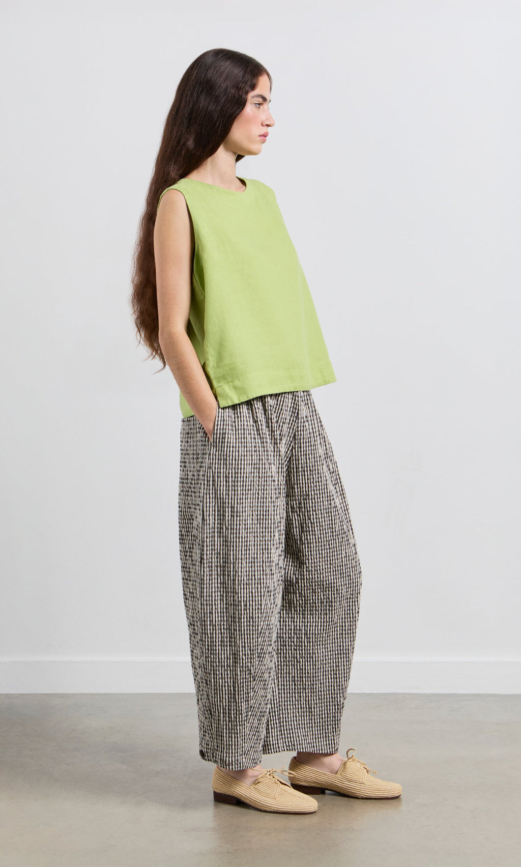 Plümo- Woman in a Linda Top - Sorrel and loose checkered pants stands sideways with hands in pockets.