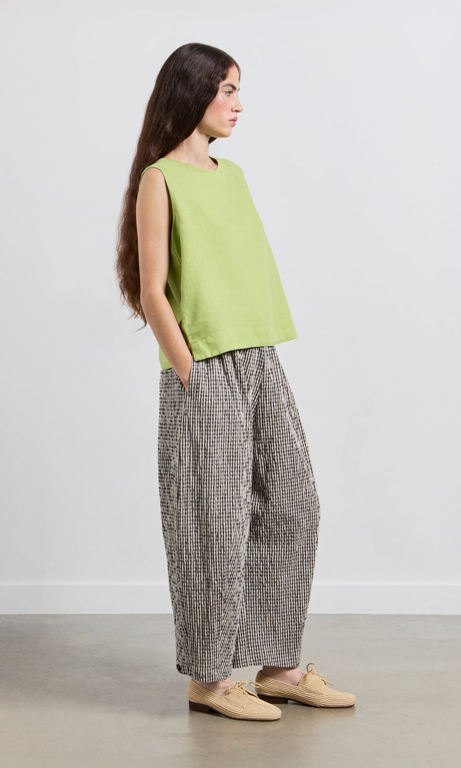 Plümo- Woman in a Linda Top - Sorrel and loose checkered pants stands sideways with hands in pockets.