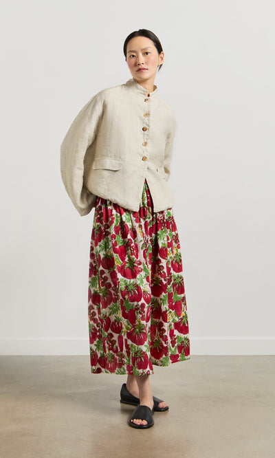 Plümo- Woman wears a beige jacket, Marzano Skirt in red cotton voile, and black sandals against a plain background.