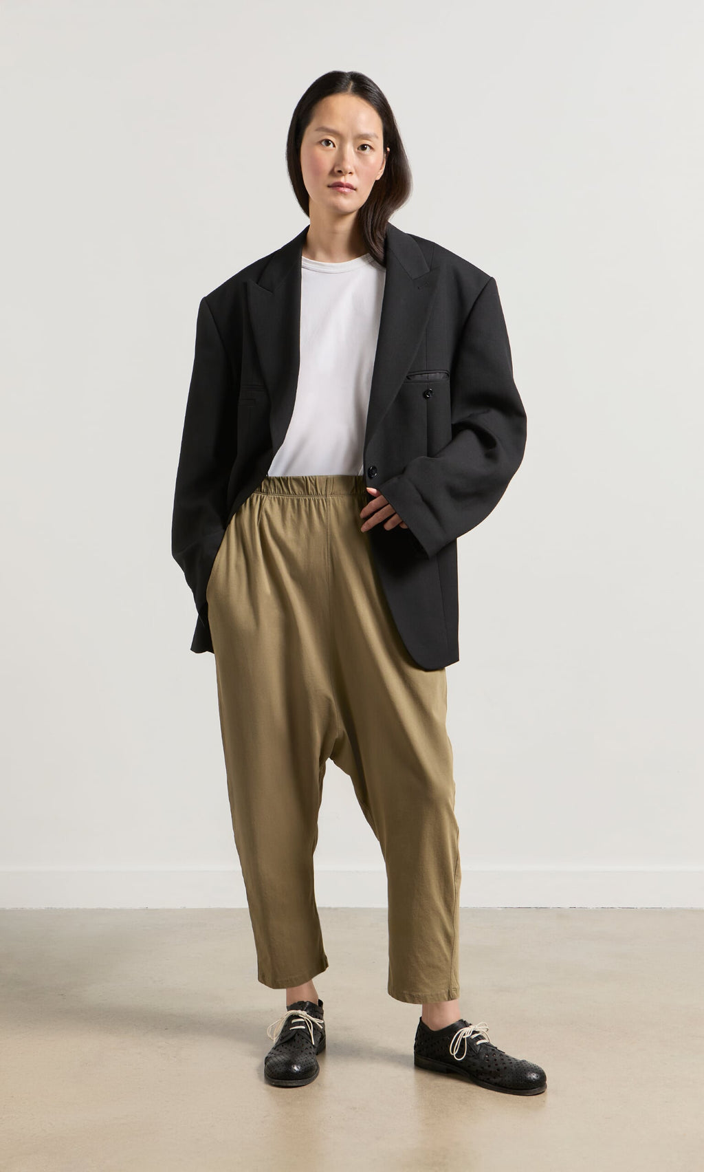 Plümo- Woman wears oversized black blazer, white tee, and Mirana Pants in classic Danish design against a plain background.
