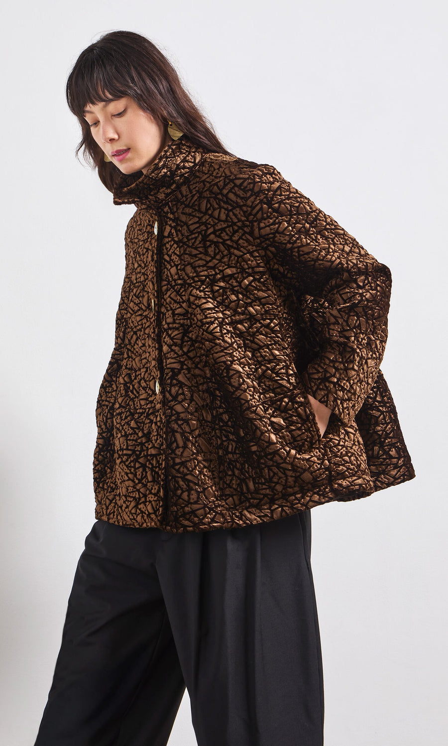 Plümo- Woman wearing the Murano Jacket with black pants, standing against a plain white background.