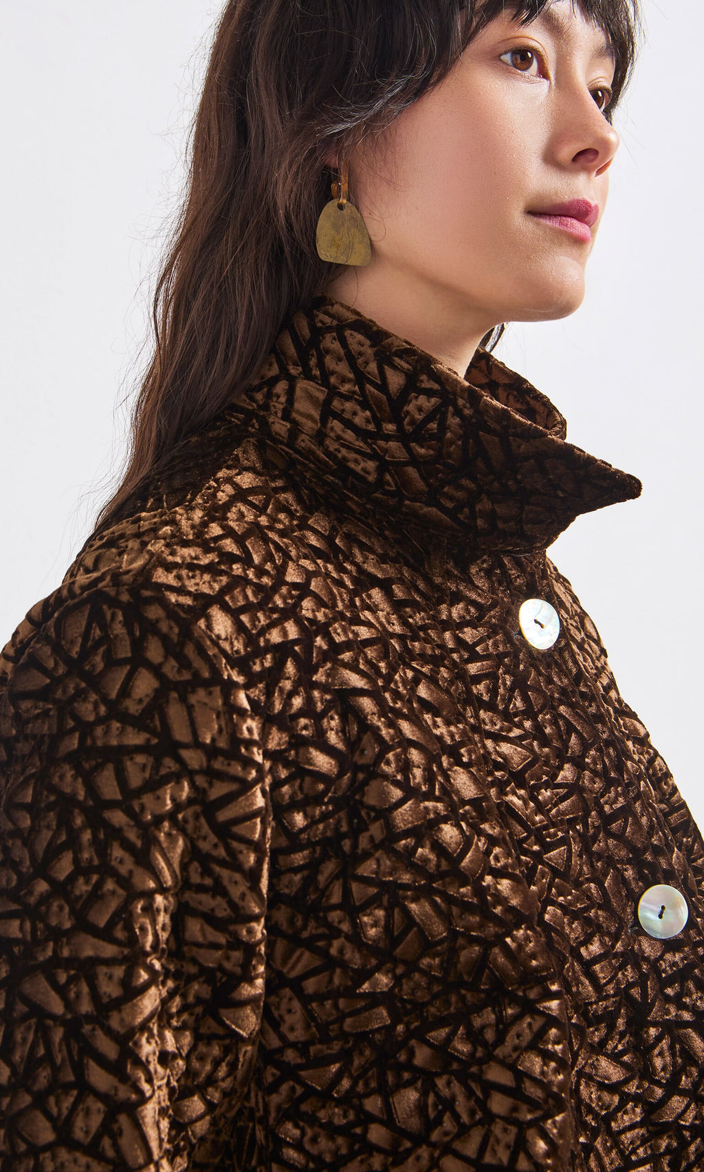 Plümo- Woman wearing the Murano Jacket—textured brown velvet with a geometric pattern and large buttons.