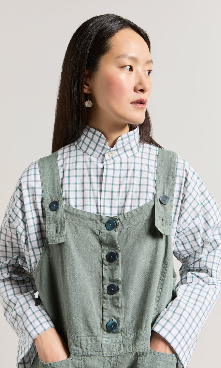 Plümo- Woman in a checkered shirt and Myrtle Linen Dungarees looking to the side against a plain background.