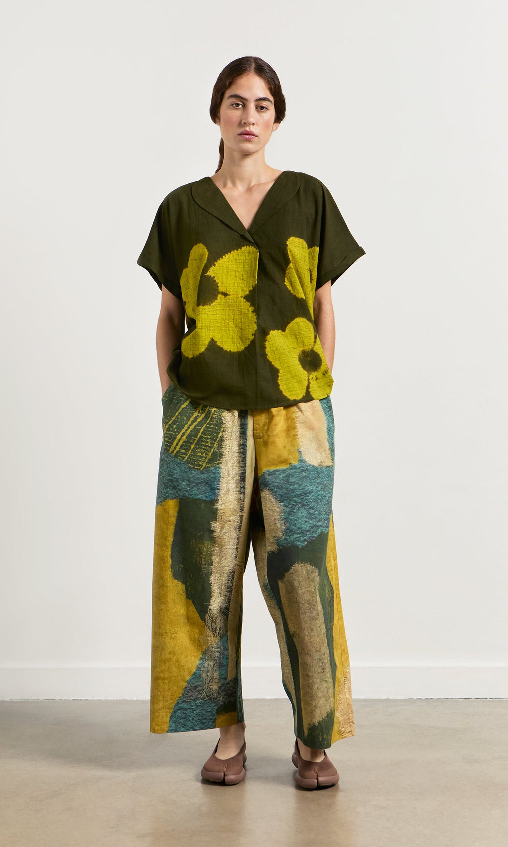 Plümo- A woman in a relaxed fit, oversized Orta Blouse with floral pattern and wide-leg pants stands against a plain background.