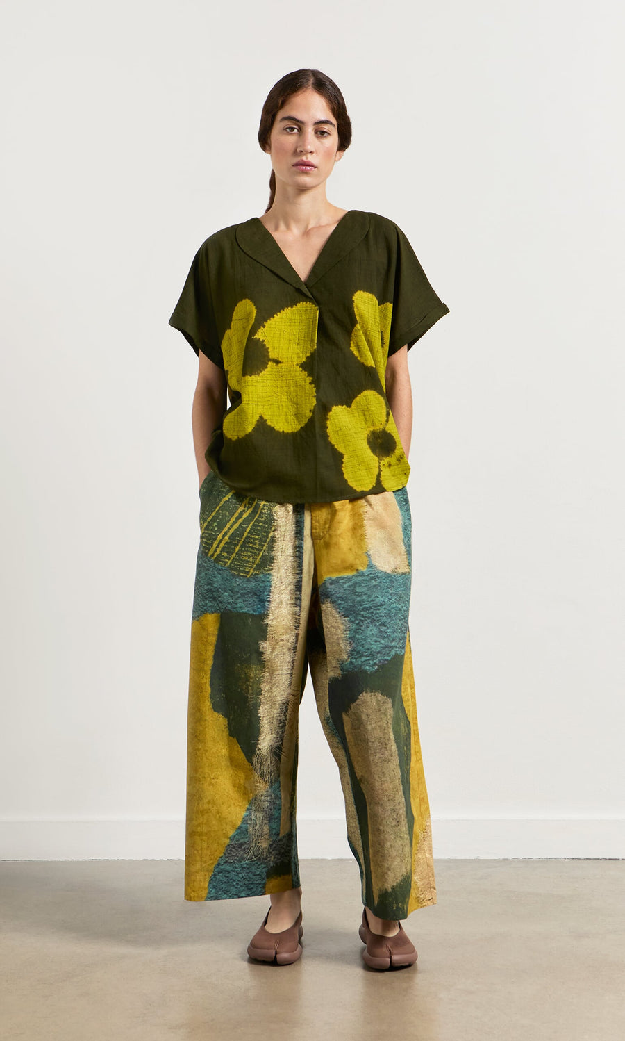 Plümo- A woman in a relaxed fit, oversized Orta Blouse with floral pattern and wide-leg pants stands against a plain background.