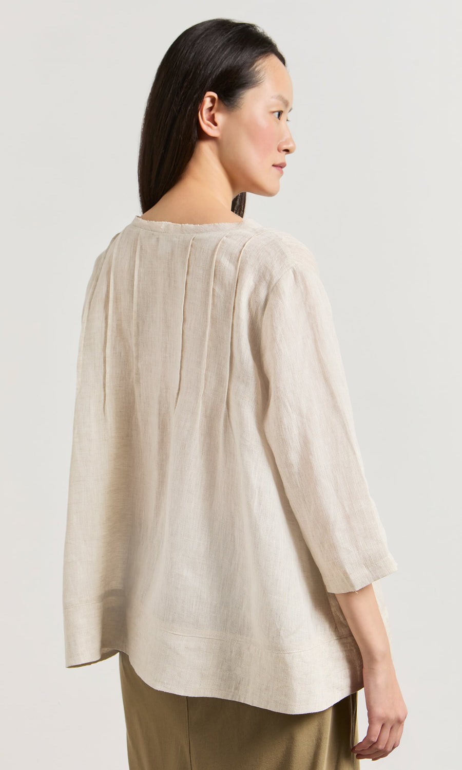 Plümo- Woman in a relaxed fit Pantry Blouse in ecru linen with three-quarter sleeves, shown from the back.