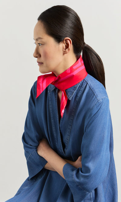 Plümo- Woman in blue denim dress with crossed arms wears a Poinsettia Necktie and looks to the side.