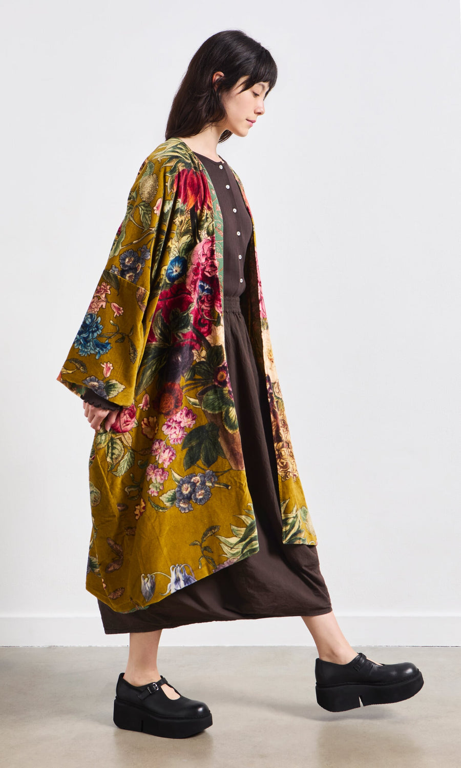 Plümo- Woman wears the Pomfret Kimono over a brown dress with black platform shoes against a plain white background.