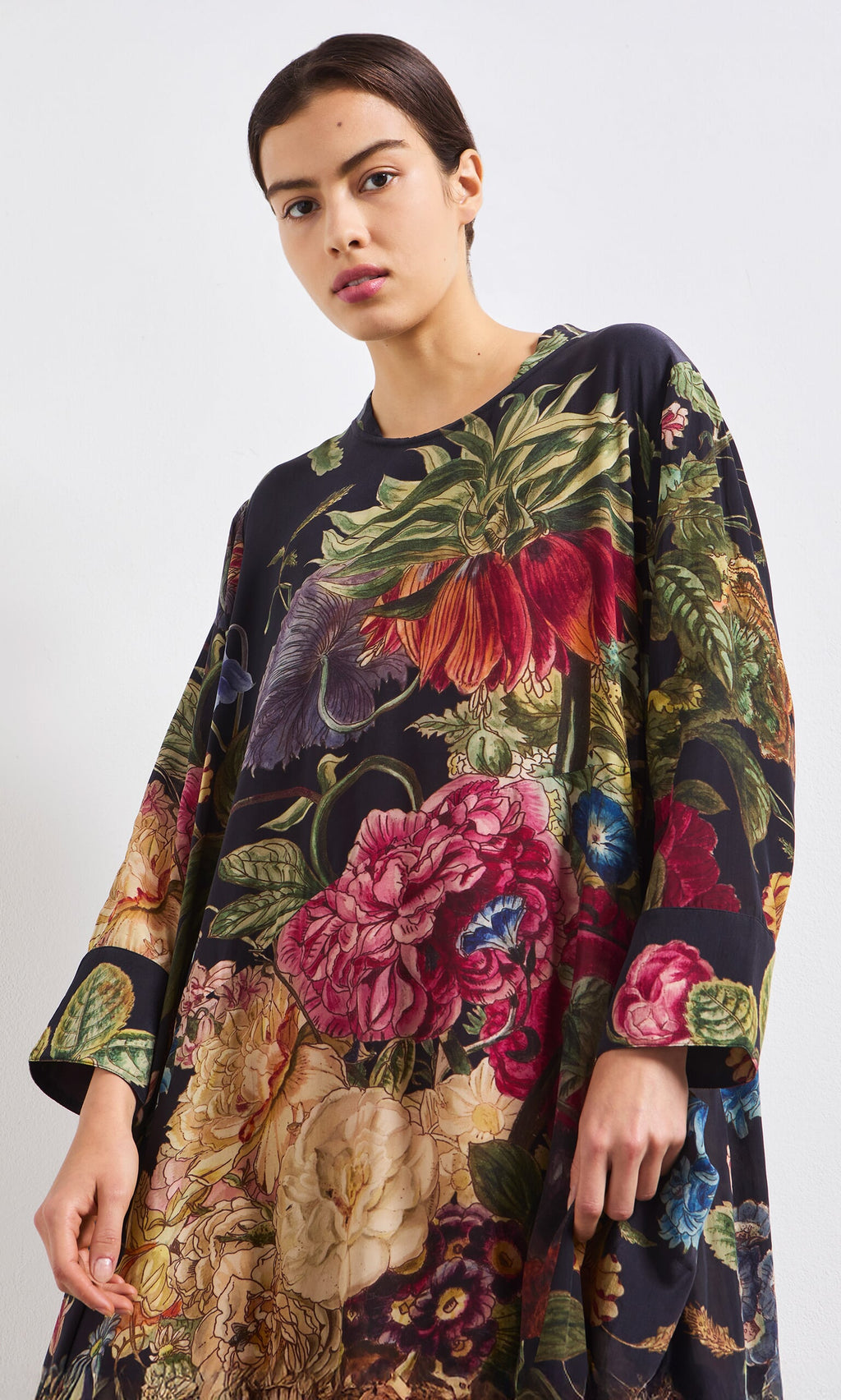 Plümo- Woman in the Primula Dress, a vibrant floral A-line, standing against a plain white background.