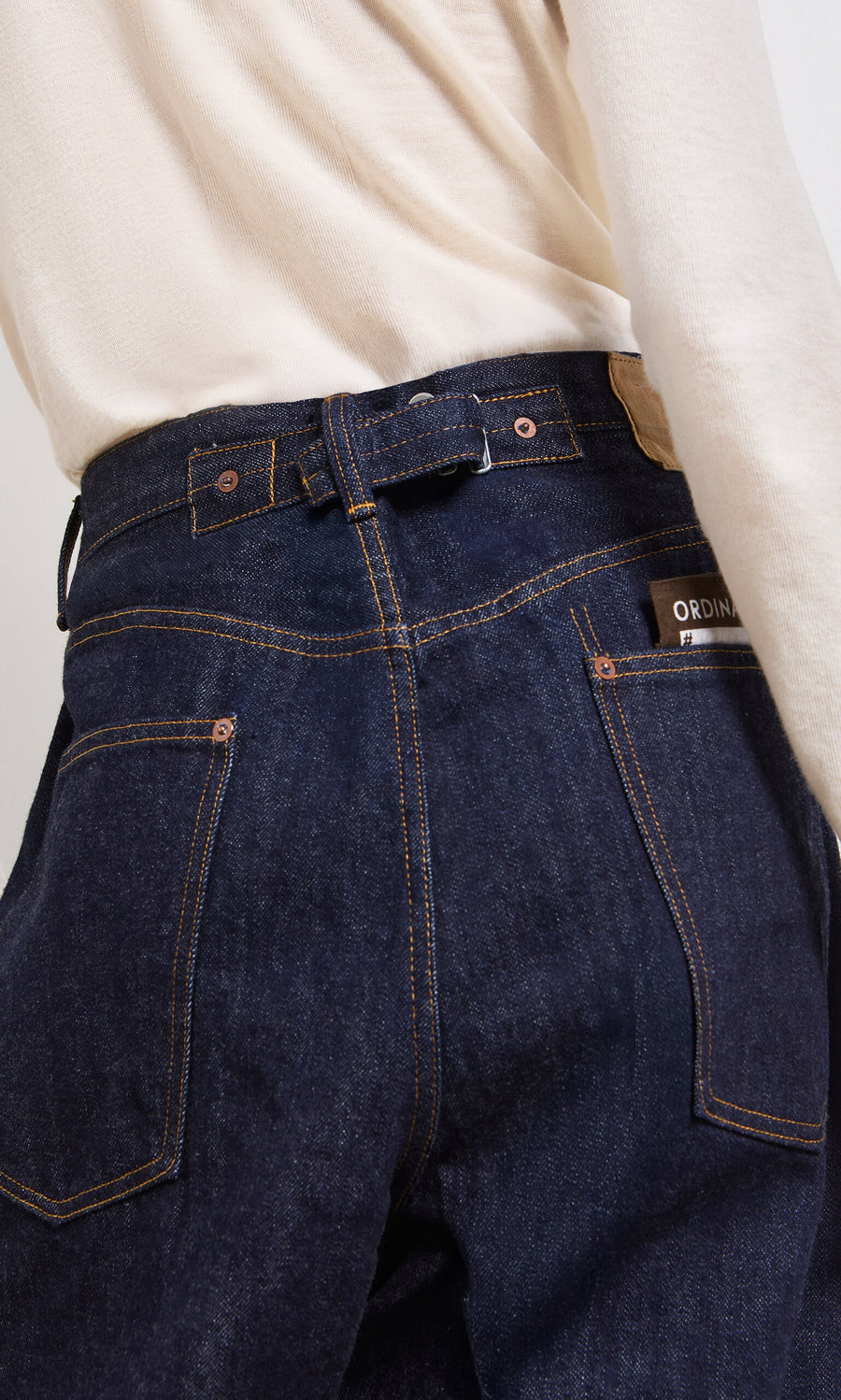 Plümo- Person wearing Japanese Raw Denim Jeans and a cream long-sleeve top, shown from the back highlighting the jeans’ pockets.