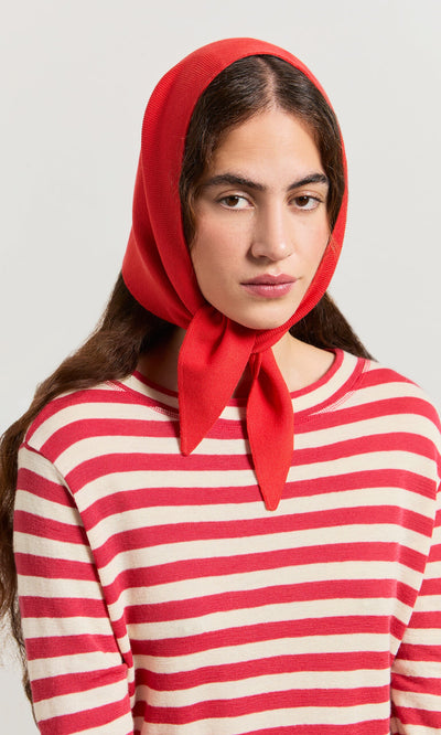 Plümo- Woman in a red headscarf and Red Stripe Top, looking at the camera with a neutral expression.