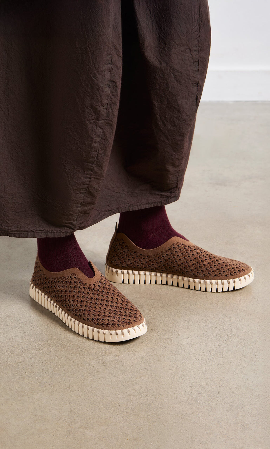 Plümo- Person wearing Tulip Shoes - Brown with white soles, burgundy socks, and a brown skirt on a light floor.