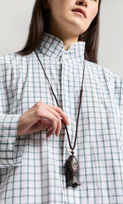 Plümo- Woman in a plaid shirt wears the Yumi Fish Necklace with a wooden fish pendant and adjustable cord, shown shoulders up.