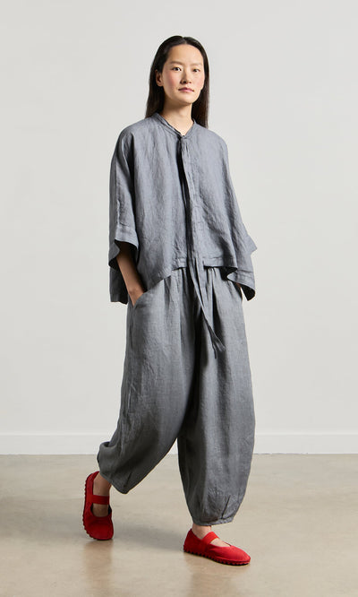 Plümo- Person in Percival Linen Pants with an elastic waist and red shoes, standing against a plain background.