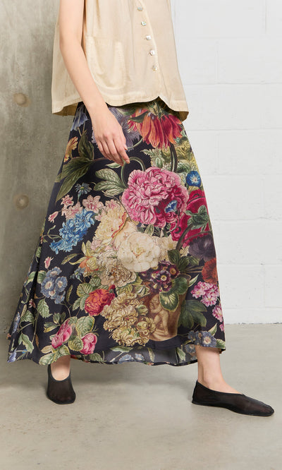 Plümo- Person wearing a beige top, Auricula Skirt, and black shoes on a concrete floor indoors.