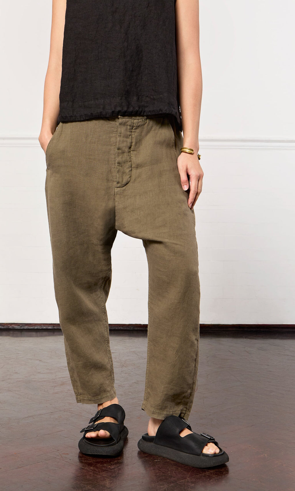 Plümo- Wearing loose olive green Caper pants, black sleeveless top, and sandals—a nod to Danish design elegance.