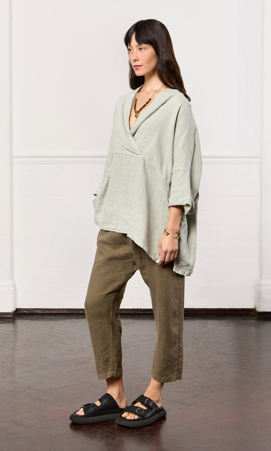 Plümo- Woman wearing the Carvey Tunic—an oversized, relaxed linen top with cropped sleeves—plus cropped pants and black sandals.