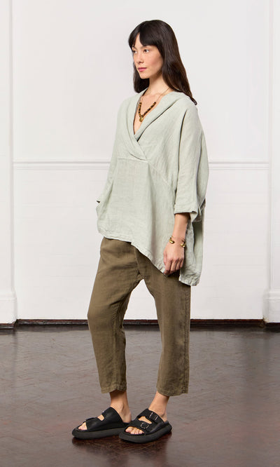 Plümo- Woman wearing the Carvey Tunic—an oversized, relaxed linen top with cropped sleeves—plus cropped pants and black sandals.
