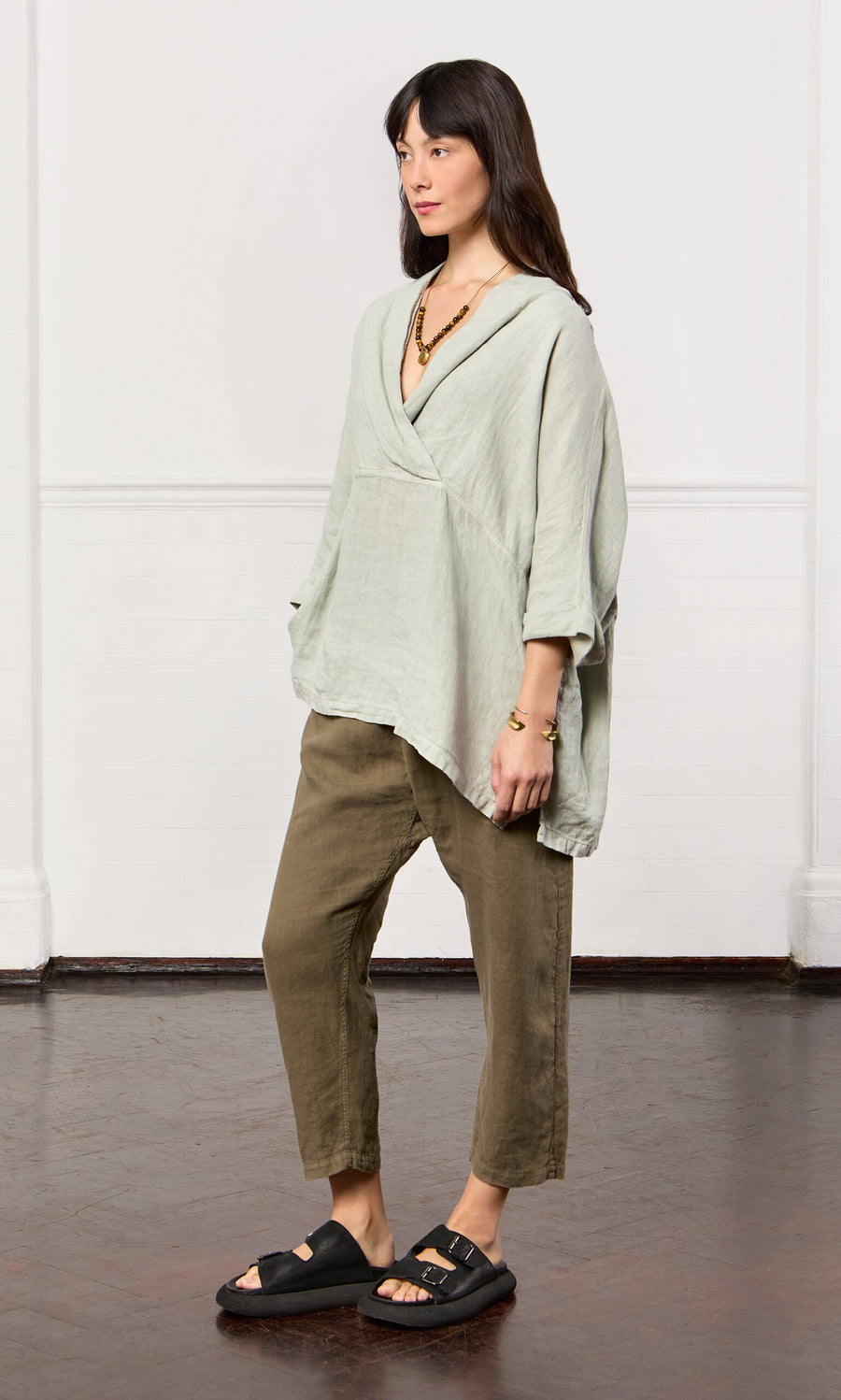 Plümo- Woman wearing the Carvey Tunic—an oversized, relaxed linen top with cropped sleeves—plus cropped pants and black sandals.