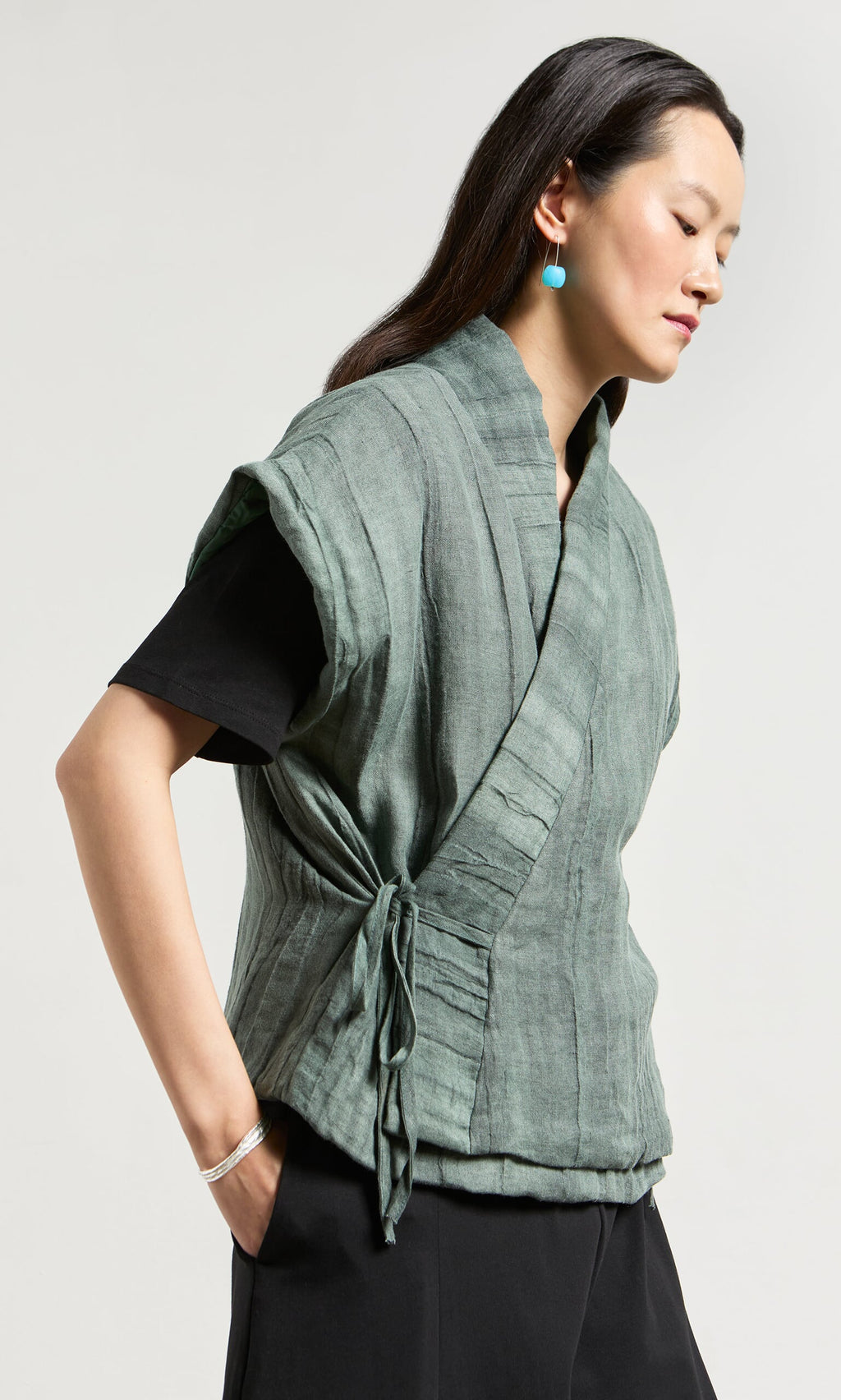 Plümo- Woman in a Fawn Gilet over black shirt, turquoise earrings—a stylish choice for transeasonal layering.