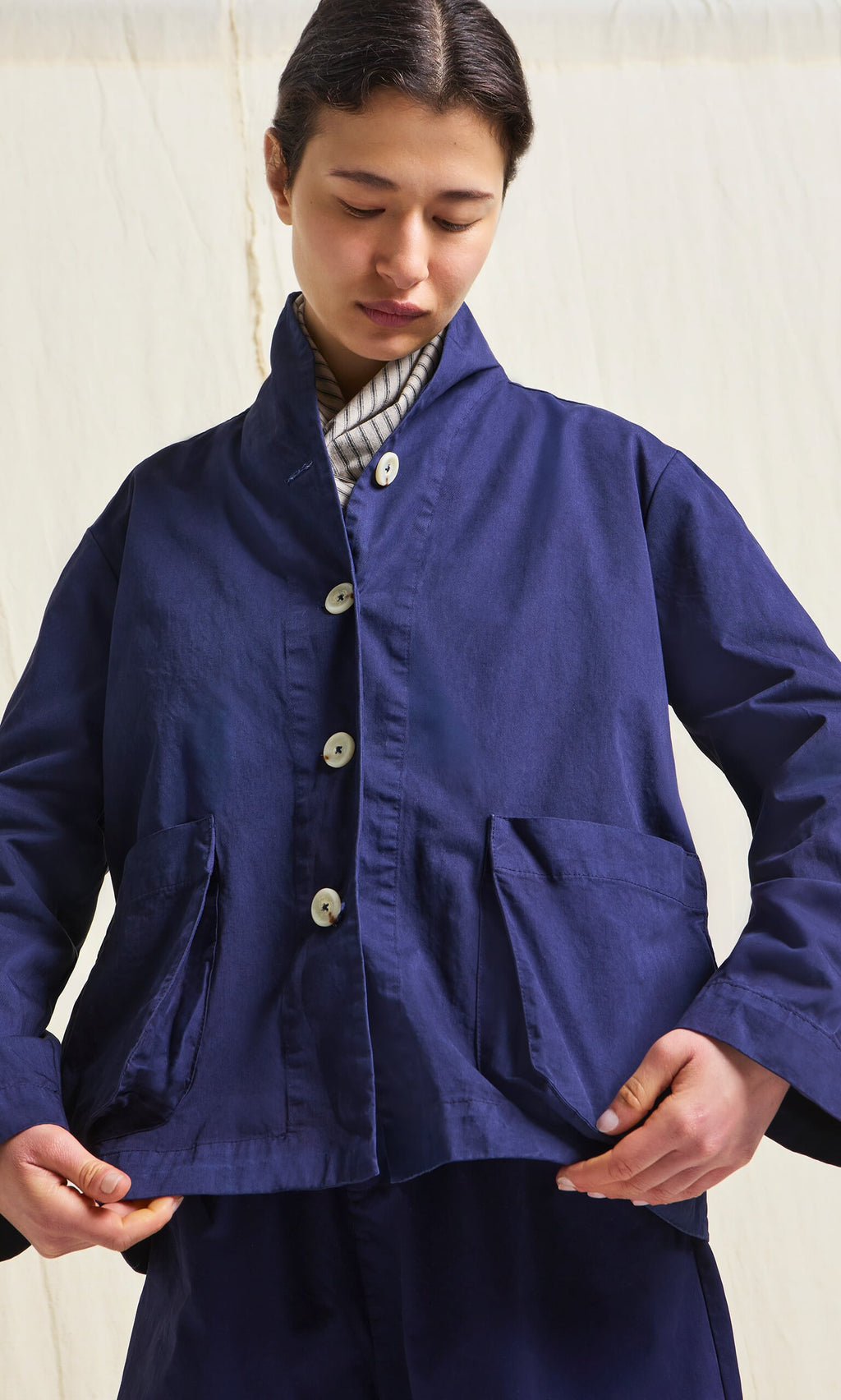 Plümo- Person wearing the Gardener's Jacket - Navy with large pockets, looking down against a light background.