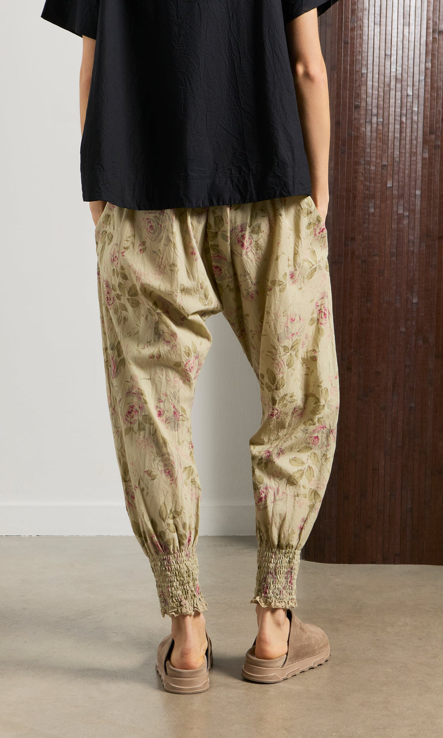 Plümo- Person in Green Floral Pantaloons, shown from behind, standing indoors on a concrete floor.