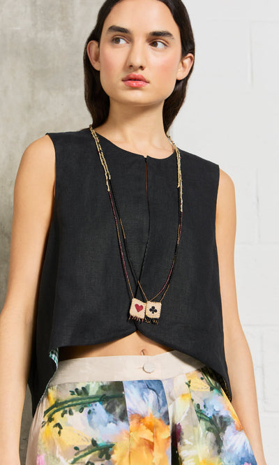 Plümo- Woman in a sleeveless black top, floral high-waisted pants, and the Hearts & Clubs Necklace.