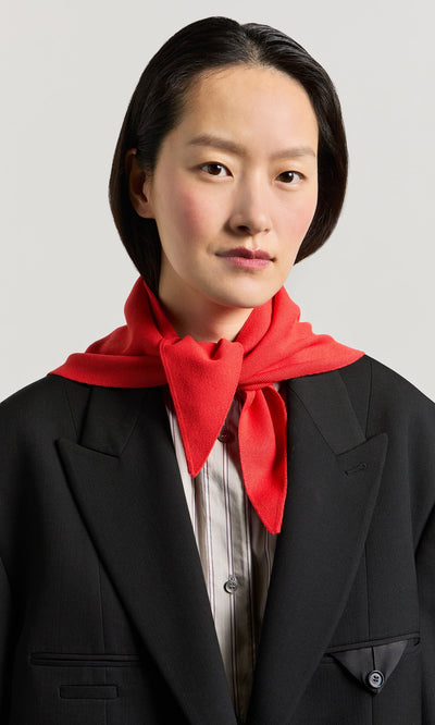 Plümo- Person with short dark hair in a black blazer, striped shirt, and the Jona Necktie - Lava around their neck.