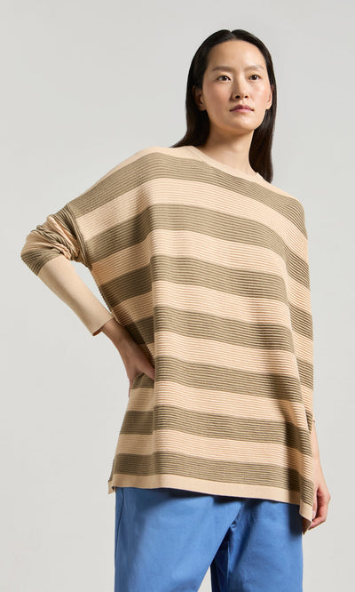 Plümo- Wearing the Jack Sweater - Silt with blue pants, a person stands against a plain light background.