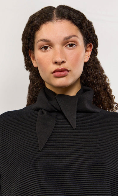 Plümo- Woman with curly hair in a black ribbed top and Jona Necktie - Black, facing forward against a light background.