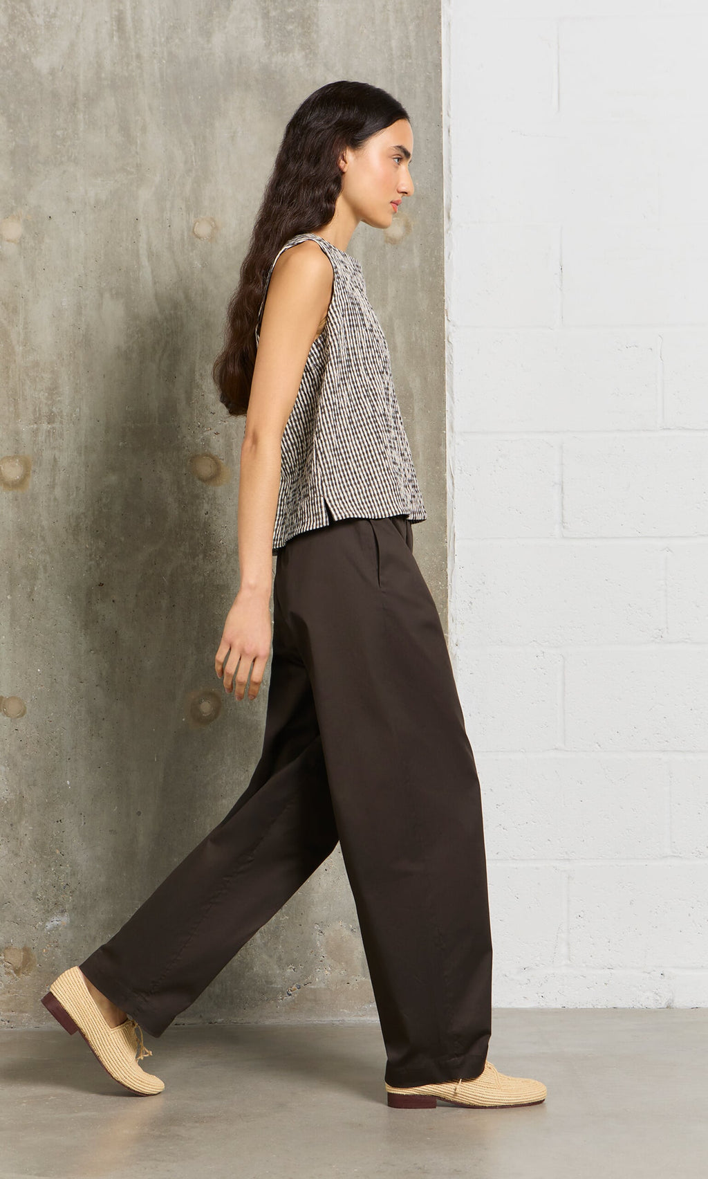 Plümo- Woman with long dark hair wears Kathleen Pants with a drawstring waist and a sleeveless patterned top indoors.