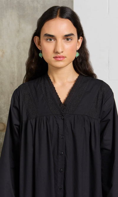 Plümo- Woman with long dark hair wearing the Lily Dress and green earrings, standing against a neutral background.