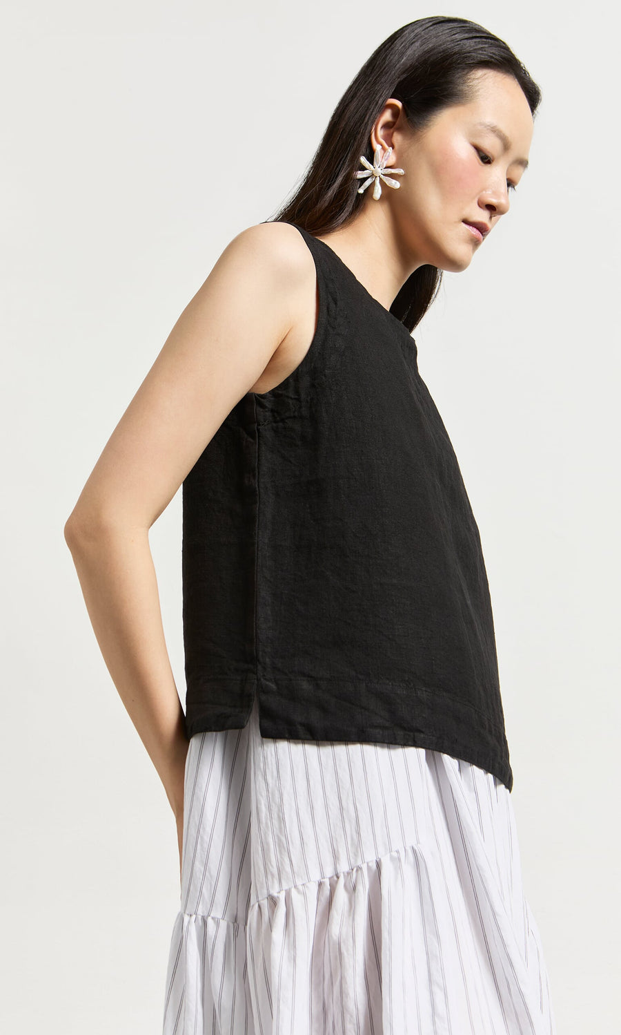 Plümo- Woman wearing the Linda Top - Solid Black over a white, striped, tiered dress with large floral earrings in San Francisco.