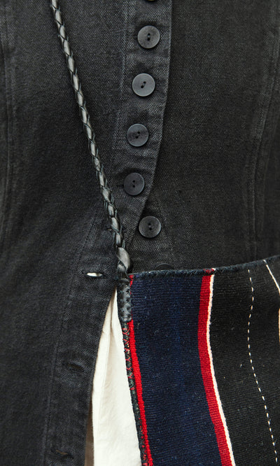 Plümo  Close-up of black shirt, braided strap, and Medina Bag—a striped Moroccan crossbody with red, white  black lines.
