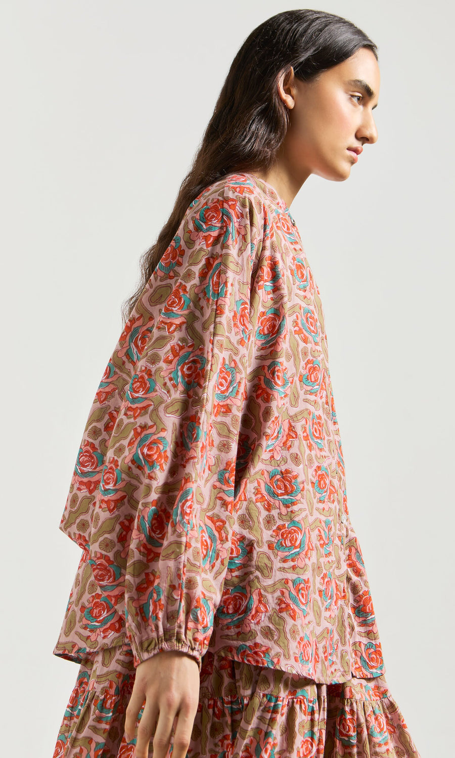 Plümo- Woman wearing the ethically made Lotus Flower Blouse, standing sideways against a plain background.