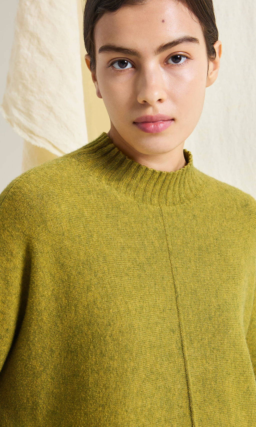 Plümo- A person wears the Wild Millet Jumper, featuring a ribbed collar, in front of a light background.