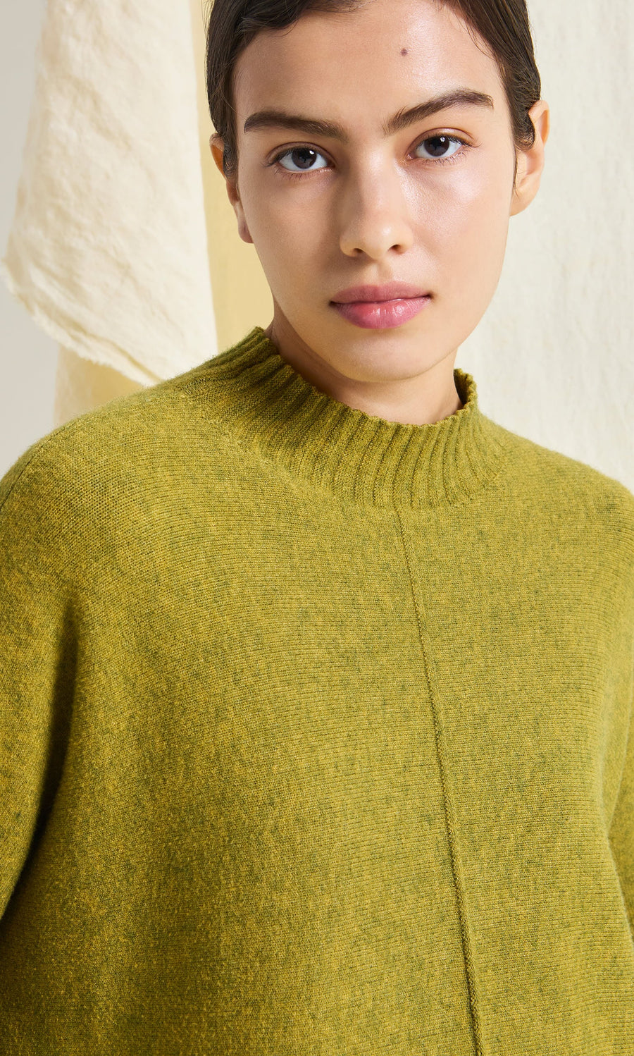 Plümo- A person wears the Wild Millet Jumper, featuring a ribbed collar, in front of a light background.