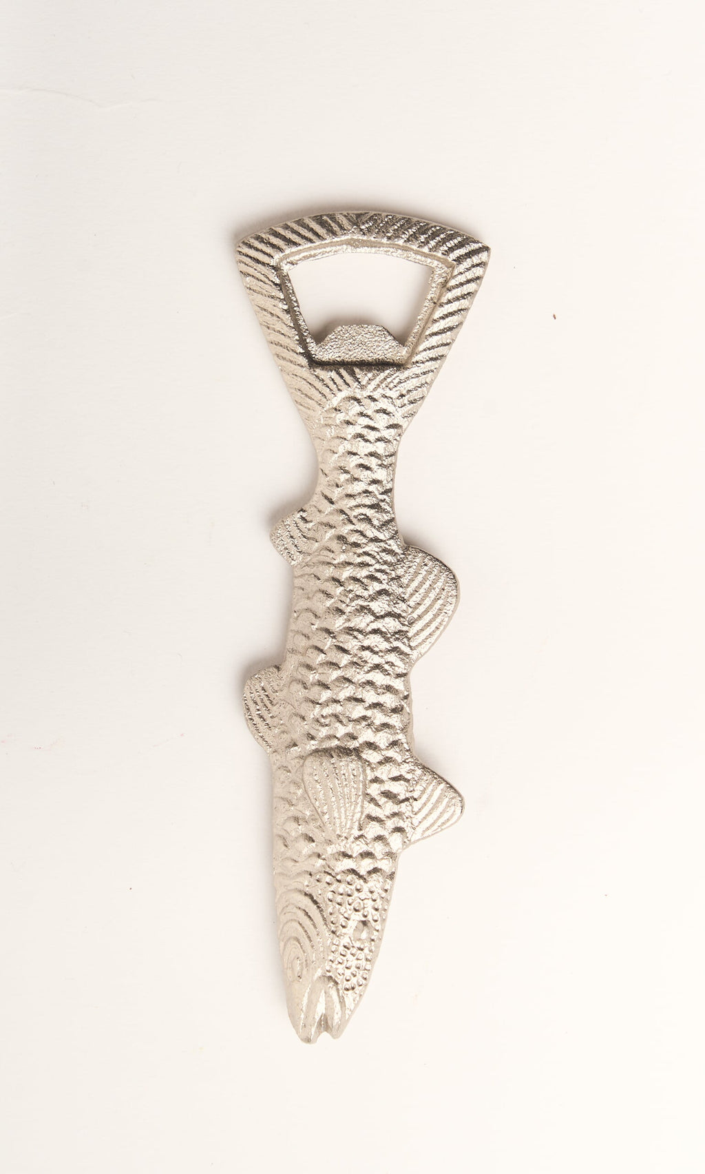 Plümo- A silver Fish Bottle Opener, shaped like a textured fish, lies on a white surface.