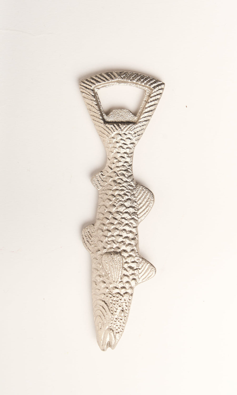 Plümo- A silver Fish Bottle Opener, shaped like a textured fish, lies on a white surface.