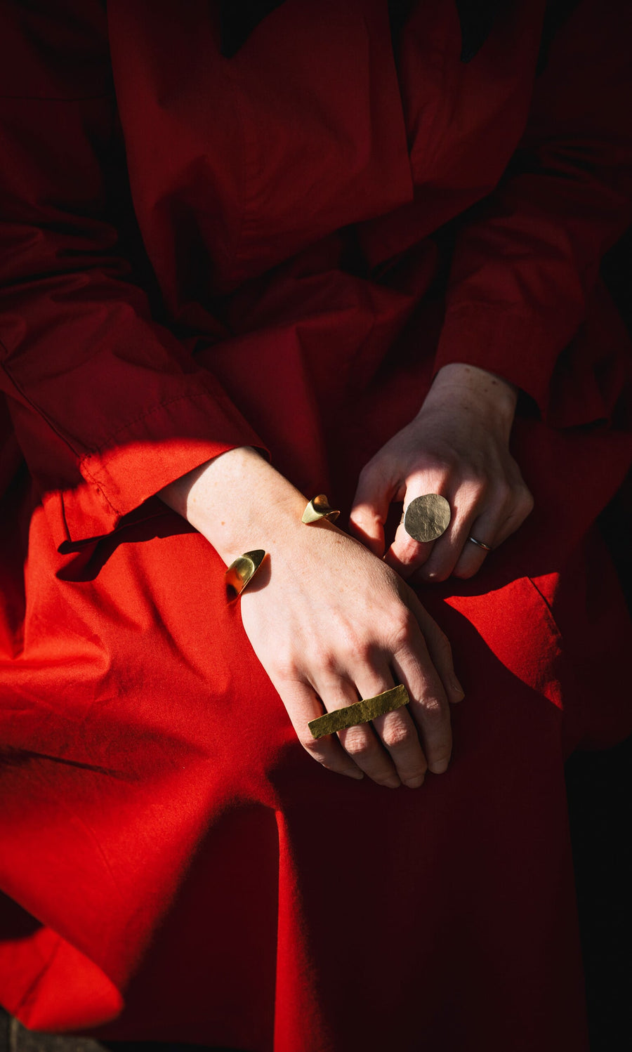 Plümo- Person in a red dress with gold bracelets wearing the Eco Silver Pebble Ring, photographed in natural light.